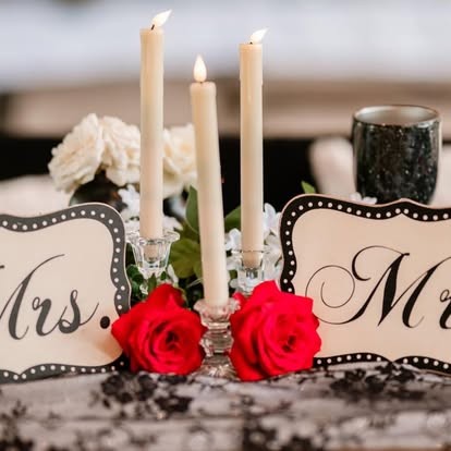 Mr and Mrs signs with taper candles and red roses on a lace table