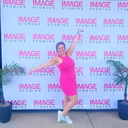 Guest posing in front of a branded step-and-repeat backdrop at a grand opening